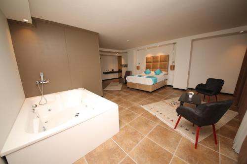 een badkamer met een bad en een slaapkamer met een bed bij SAFRAN GERMİA PALaS in Bostanbükü