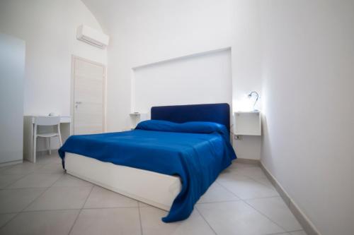 uma cama azul num quarto branco com uma mesa em ELISA Dependance Centro em Vietri