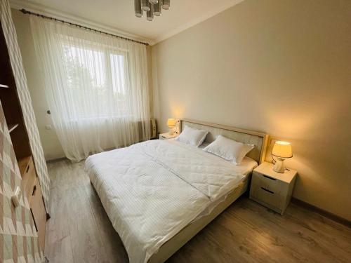 a bedroom with a white bed with two lamps at Yas Apartment in Samarkand