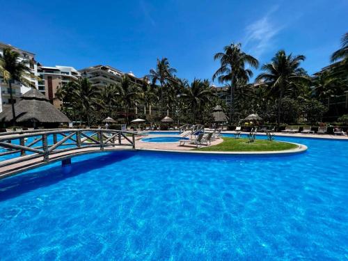 a large pool with a bridge and palm trees at Beachfront 2 bedroom Condo in Playa Royale Resort, Nuevo Vallarta in Nuevo Vallarta