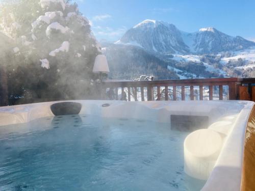 a hot tub with a view of a snowy mountain at Chalet Alpaga Location de prestige in Manigod