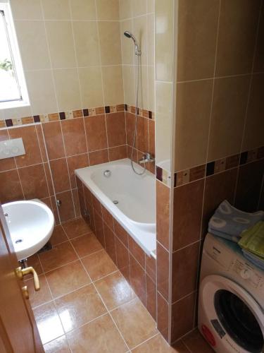 a bathroom with a tub and a sink and a washing machine at Porto One Apartment in Đenovići