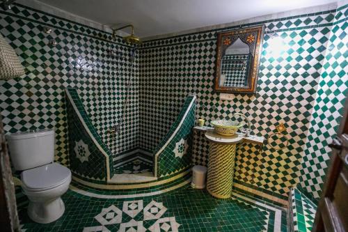 a bathroom with a toilet and a shower with green and white tiles at Riad Le Moucharabieh in Fès