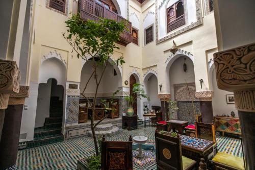 a building with a hallway with tables and chairs at Riad Le Moucharabieh in Fès