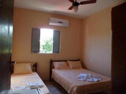 1 dormitorio con 2 camas y ventilador de techo en Candairó Hotel Pousada en Cananéia
