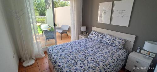 a bedroom with a bed with a blue comforter and a window at Oasis Hoyo 12 - Oliva Nova playa MET&GOLF in Oliva