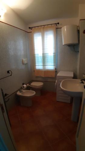 ein Bad mit einem WC, einem Waschbecken und einem Fenster in der Unterkunft Le pavoncelle 1 in Calasetta