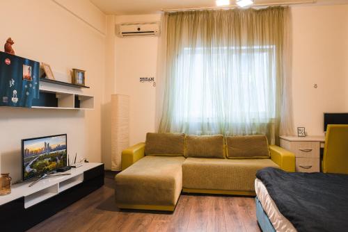 a living room with a couch and a tv and a window at Apartament Ultracentral, Piata Romana in Bucharest
