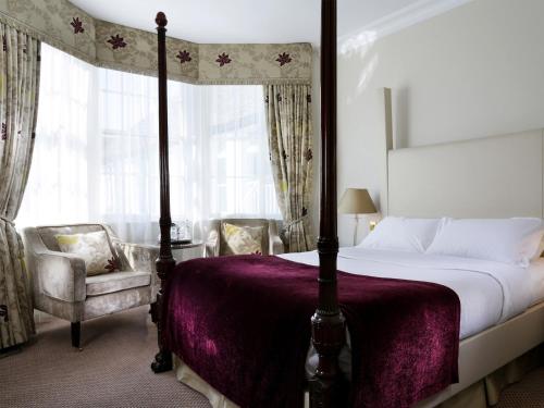 a bedroom with a canopy bed and two chairs at Macdonald Bear Hotel in Woodstock