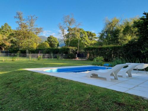 a swimming pool with two white chairs in the grass at Casa San Lorenzo in San Lorenzo