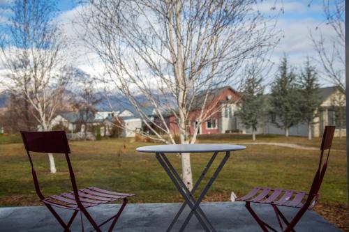 two chairs sitting around a table in a yard at Brassed Off Modern Arrowtown Studio in Arrowtown