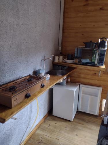 a kitchen with a stove and a sink and a refrigerator at Cabanas Quatro Irmãos - Beira Rio in Urubici