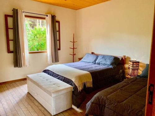 un dormitorio con una cama y una ventana en Chalés Alcantilado - Morada Sol e Lua, en Visconde De Maua