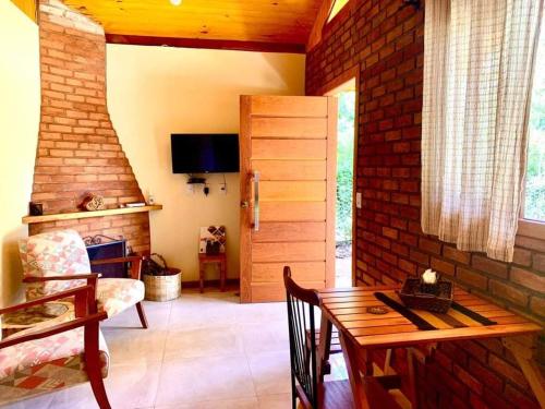 a living room with a table and a brick wall at Chalés Alcantilado - Morada Sol e Lua in Visconde De Maua