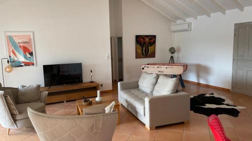 a living room with a couch and a tv at Magnifique Villa Domaine de Biglette in Baie-Mahault