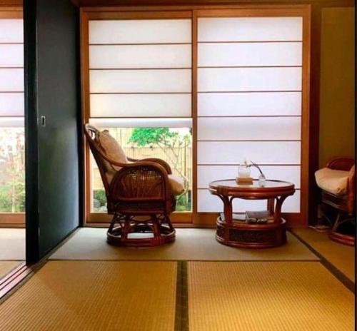 Zimmer mit einem Stuhl und einem Tisch vor einem Fenster in der Unterkunft Vacation house月yue in Tokushima
