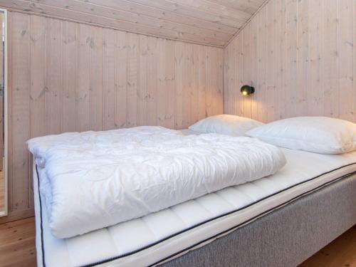 a large white bed in a room with wooden walls at 6 person holiday home in Ulfborg in Ulfborg