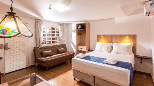 a bedroom with a bed and a couch and a chair at Hotel Chalet Monet - Granja Vianna in Cotia