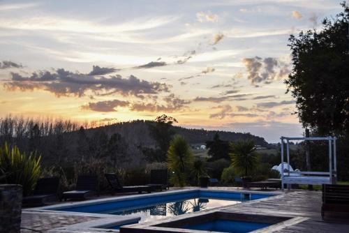 a swimming pool with a sunset in the background at Valle de Domos - Minas in Minas