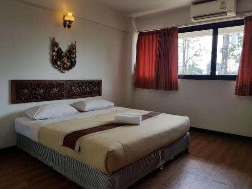 a bedroom with a large bed and two windows at Punya Garden Hotel in Ban Wang Won