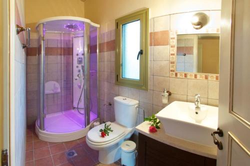 y baño con ducha, aseo y lavamanos. en Villa Maria, en Kaligata