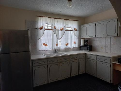 a kitchen with white cabinets and a sink and a window at More Than Beauty Properties in Tortola Island
