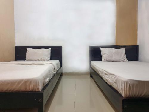 two beds sitting next to each other in a room at Grand Azizah Makassar RedPartner in Makassar