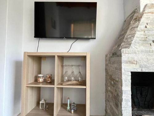 a television hanging on a wall above a fireplace at Azzurra House in Marina di Pisa