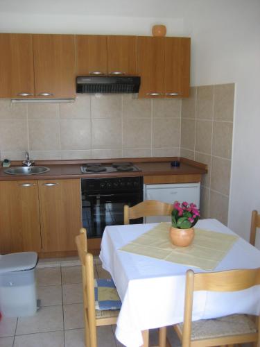 a kitchen with a table with a vase of flowers on it at Apartments Katica in Lumbarda