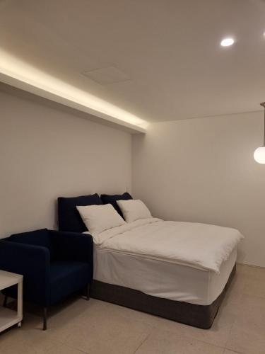 a bedroom with a bed and a blue chair at Laon on 37 in Tongyeong
