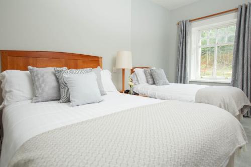 a bedroom with three beds with white sheets and a window at Kilcoran Lodge Hotel & Leisure Centre in Cahir