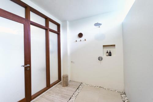a bathroom with white walls and a glass door at El Tropico Boutique Hotel in Kuta Lombok