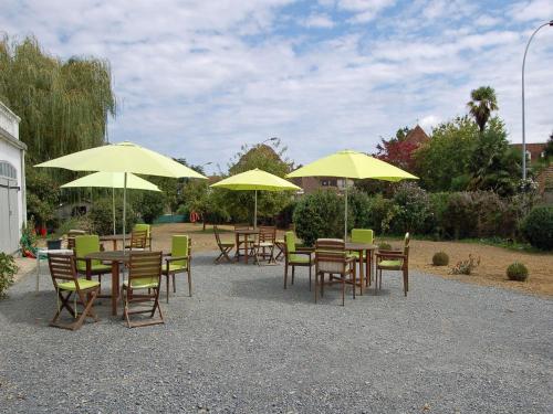 a group of tables and chairs with yellow umbrellas at La Maison d'Antan in Arzacq-Arraziguet