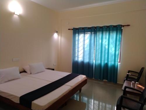 a bedroom with a bed and a window with blue curtains at Shamrock Inn in Cochin