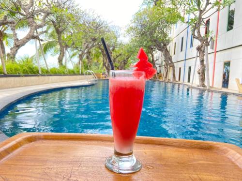 a drink sitting on a table next to a pool at Singaraja Hotel - CHSE Certified in Singaraja