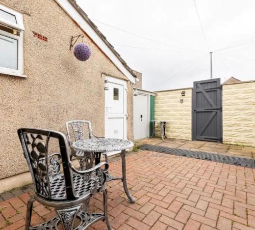 a patio with a table and a chair next to a building at Shelley’s Seaside Stay (Garden/ Double Drive) in Porthcawl