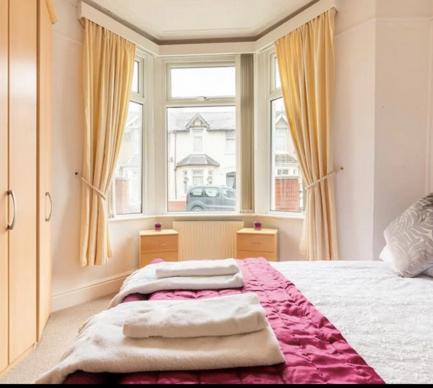 a bedroom with a bed with towels on it at Shelley’s Seaside Stay (Garden/ Double Drive) in Porthcawl