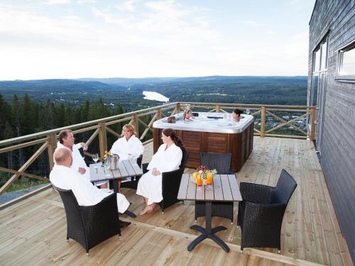 a group of people sitting around a hot tub on a deck at Hotell Hallstaberget in Sollefteå