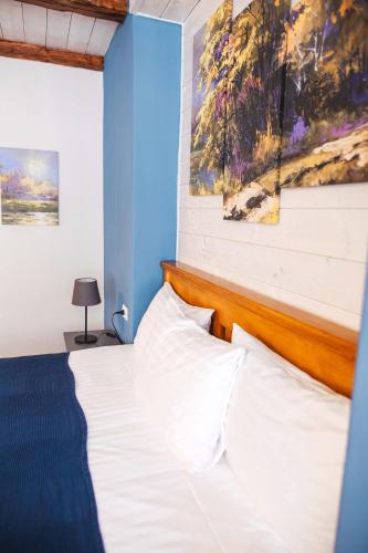 a bedroom with a white bed with a blue wall at CASA HINTZ Transilvania in Făgăraş