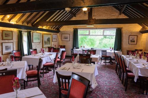 un restaurante con mesas y sillas blancas y una ventana en Brown Trout Golf & Country Inn en Aghadowey