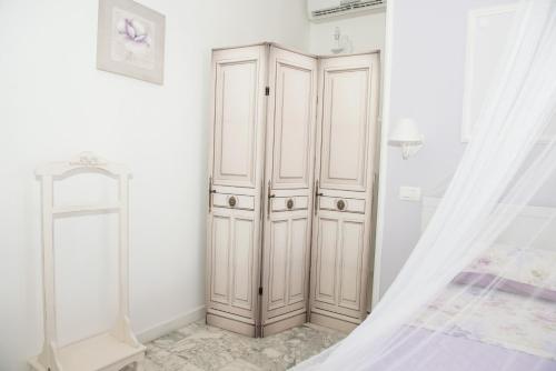 a white bedroom with a wardrobe and a curtain at I Citri in Taranto