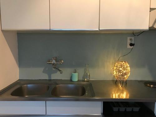 a kitchen sink with a light next to it at Studio Bee Home in De Haan