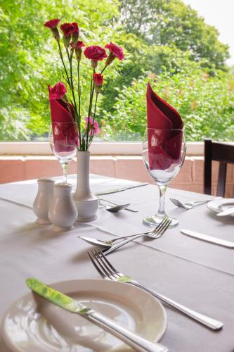 a table with two wine glasses and flowers on it at Brown Trout Golf & Country Inn in Aghadowey