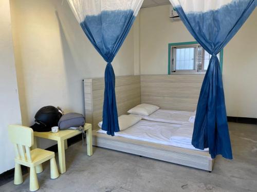 a bedroom with a bed with blue curtains and a chair at Wanluan Organic Bookstore in Wanluan