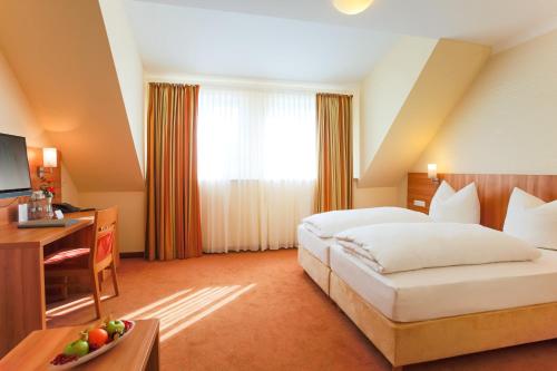 a hotel room with a large bed and a desk at Berggasthof Banzer Wald in Bad Staffelstein