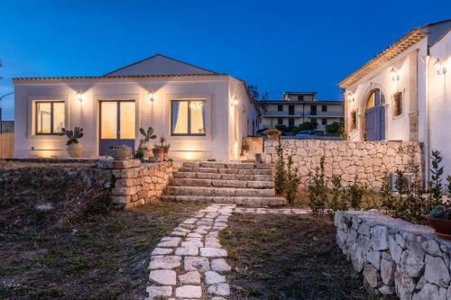 een wit huis met een stenen muur en een trap bij MichaEl garden in Noto
