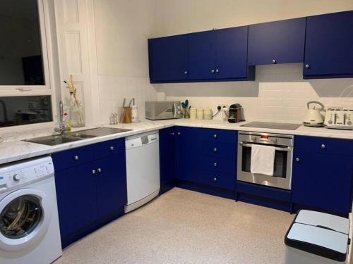 uma cozinha com armários azuis e uma máquina de lavar roupa em Lovely 3 bedroom family friendly cottage in North Berwick em North Berwick