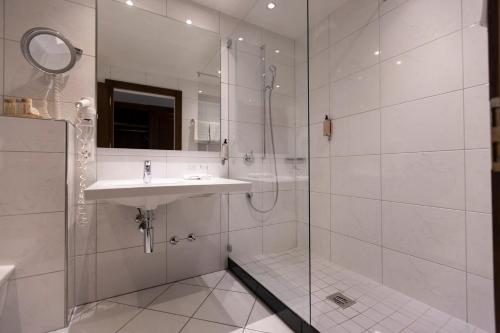 a white bathroom with a sink and a shower at Swiss-Chalet Merlischachen - Romantik Schloss-Hotel am See in Küssnacht