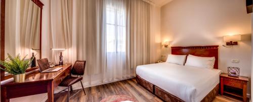 a hotel room with a bed and a desk and a window at Satori Hotel in Haifa