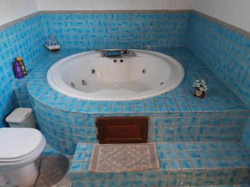 a blue tiled bathroom with a tub and a toilet at Villa sarda in Assemini